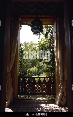 Innenansicht der drapiert, die Türen öffnen sich zu einem Balkon mit Blick auf einen Garten. Stockfoto