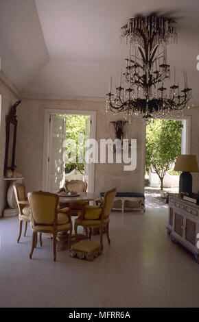 Traditionellen Speisesaal mit hohen Decken, Wände aus Stein, Marmorboden, runde antikem Esstisch und Stühlen, und einem prunkvollen Kronleuchter aus Kristall. Stockfoto