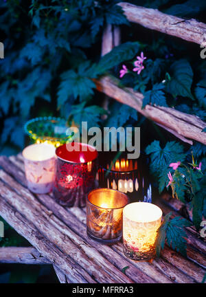 Kerzen in der Halterung auf hölzernen Sitzbank im Freien Stockfoto