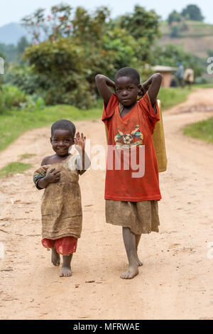 Zwei afrikanische Kinder auf einem Sandweg, winken, in der Nähe von Lake Mutanda, Uganda Stockfoto