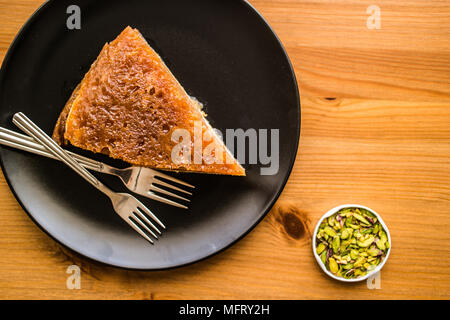 Türkische traditionelle Dessert Ekmek Kadayifi/Brotpudding auf einer hölzernen Oberfläche. Stockfoto