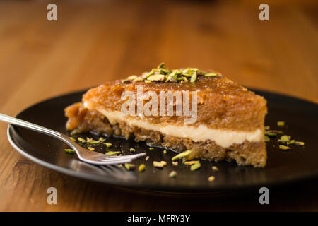 Türkische traditionelle Dessert Ekmek Kadayifi/Brotpudding auf einer hölzernen Oberfläche. Stockfoto