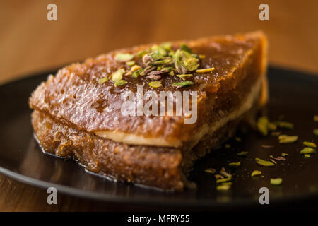 Türkische traditionelle Dessert Ekmek Kadayifi/Brotpudding auf einer hölzernen Oberfläche. Stockfoto