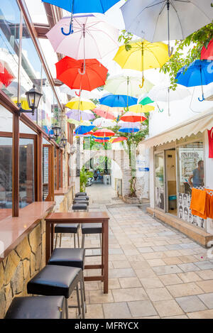 Bunte sonnenschirme Herunterhängen an engen Gassen von Bodrum mit weissen Häusern im griechischen Stil Bodrum Türkei. Am 23. August 2017 Stockfoto