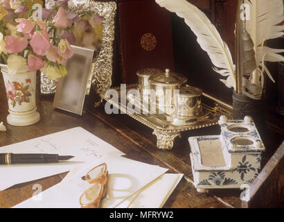 Schreiben Materialien auf Holz Schreibtisch inkl. Kugelschreiber und Papier silber Tinte Brunnen und Vase mit Blumen. Stockfoto