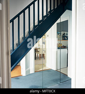 Moderne Flur mit blauen Holztreppe und einer Spiegelwand reflektierende angrenzende Zimmer. Stockfoto