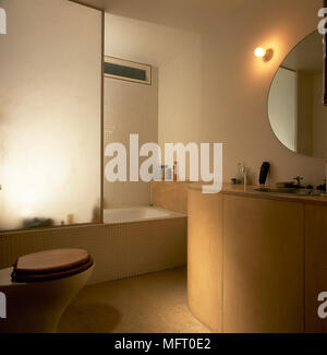 Modernes Bad mit Fliesen, Badewanne mit Milchglas partition, Waschbecken, und sanfter Beleuchtung. Stockfoto