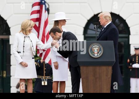 Der französische Präsident Emmanuel Längestrich, küsst die Hand seiner Frau Brigitte Längestrich, Links, als US-Präsident Donald Trump, rechts, und die erste Dame Melania Trump Blick auf während der formellen Begrüßungszeremonie auf dem Rasen des Weißen Hauses vom 24. April 2018 in Washington, DC. Längestrich ist auf einem Staatsbesuch in Washington, der erste Präsident seit Trump Amt übernahm. Stockfoto