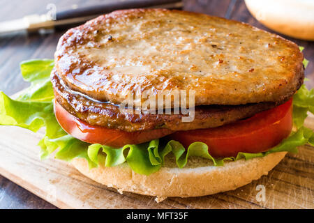 Doppelklicken Sie Burger mit der Türkei Fleisch, Salat und Tomaten auf Holz- Oberfläche. FastFood Konzept. Stockfoto