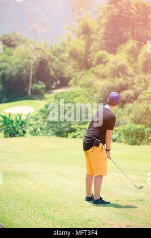Golfspieler schlagen der Schuß mit dem Club auf Kurs während der Sommerferien, junge Golf spielen auf einem Golfkurs in der Sonne Stockfoto