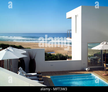 Eine von außen ein weißes modernes Strand Haus mit einem Swimming Pool, Liegestühle und Sonnenschirme Stockfoto
