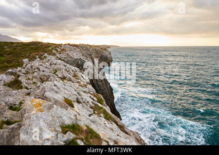 Landschaftsansicht der kantabrischen Küste und Klippen bei einem bewölkten Sonnenuntergang in der Nähe von Gulpiyuri Strand (Schiffe, Llanes, Oriente, Asturien, Spanien) Stockfoto