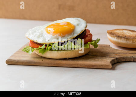 Offene Hamburger mit Ei, Salat und Tomaten auf Holz- Oberfläche. FastFood. Stockfoto