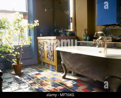 Land Bad Detail mit dekorativen Mosaikfußboden und Waschbecken, freistehende freistehende Badewanne und eine Topfpflanze am Fenster. Stockfoto