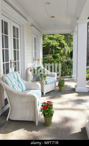 Korbsessel mit blauen und weißen Streifen Kissen auf Haus veranda Stockfoto