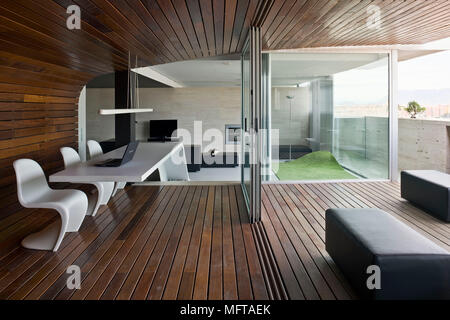 Verner Panton Stühle am Tisch in der modernen holzgetäfelten Zimmer mit Blick auf den Outdoor Terrasse Stockfoto