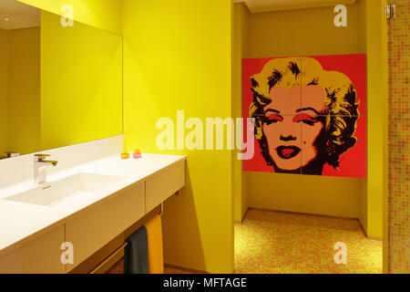 Spiegel über dem Waschbecken im Regal in der zeitgenössischen gelb Bad mit Andy Warhol Marilyn Monroe Siebdruck auf Wand Stockfoto