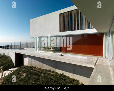 Von außen ein modernes Haus auf verschiedenen Ebenen mit Terrasse mit Blick auf den Ozean Stockfoto