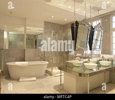 Geräumige, gefliestes Badezimmer mit zwei Waschbecken im Zentrum der Insel, eine freistehende Badewanne, und verzierten Spiegel. Stockfoto
