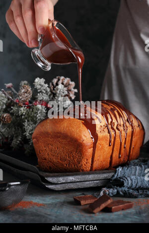 Frau giesst geschmolzene Schokolade auf einem Schokoladenkuchen, im neuen Jahr Dekorationen Stockfoto