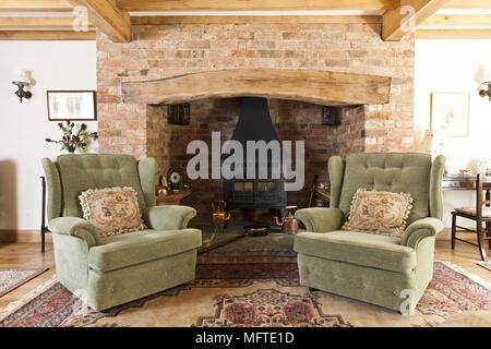 Zwei gepolsterte Sessel vor dem Kamin im Landhausstil Stockfoto