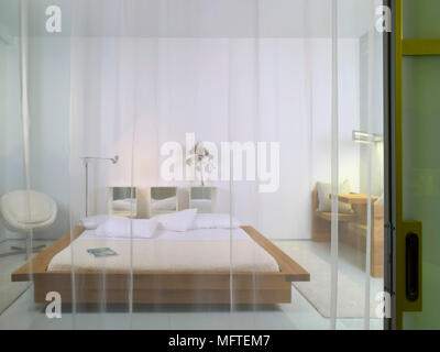 Holz- plattform Bett im modernen Schlafzimmer durch schiere Vorhang gesehen Stockfoto