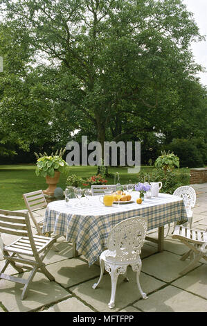Tisch und Stühle aus Holz und Metall auf der Terrasse im Garten. Stockfoto