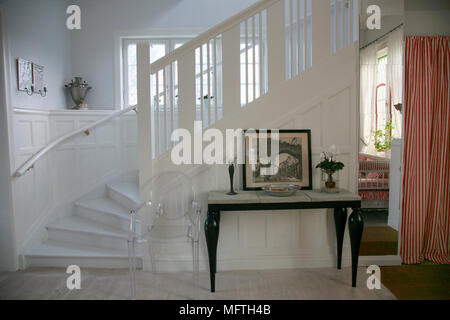 Philippe Starck Louis Ghost transparente Stuhl am Tisch in den Flur mit Treppe zum Seite Stockfoto