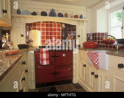 Küche im Landhausstil mit einem großen roten Backofen- und Fliesenboden. Stockfoto