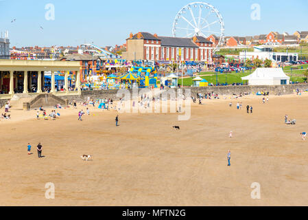 Leute genießen Sie einen Spaziergang am Strand und in der Sonne zu sitzen, an einem warmen Frühlingstag auf Barry Island, Wales Stockfoto