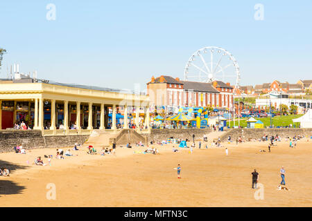 Leute genießen Sie einen Spaziergang am Strand und in der Sonne zu sitzen, an einem warmen Frühlingstag auf Barry Island, Wales Stockfoto