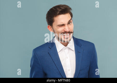 Lustige Geschäftsmann wink und Flirt an der Kamera. Business Personen Konzept, reich und der Erfolg. Innen-, Studio shot auf hellblauem Hintergrund Stockfoto