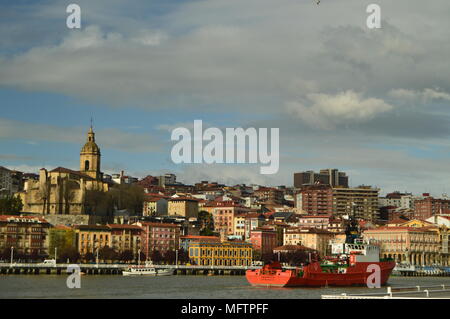 Blick auf die Kirche und Gebäude des Porugalete bei Sonnenaufgang mit einem Boot Überqueren der Ria Capture Chuck von Getxo. Architektur Geschichte Reisen. 25. März Stockfoto