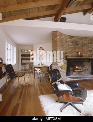 Wohnzimmer mit Parkettboden und Decke retro Leder Charles Eames Stuhl und großen gemauerten Kamin Stockfoto