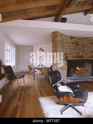 Wohnzimmer mit Parkettboden und Decke retro Leder Charles Eames Stuhl und großen gemauerten Kamin Stockfoto