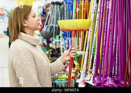 Frau entscheidet, ein Fußboden Bürste im Store. Stockfoto