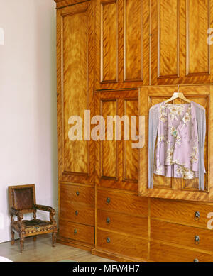 Detail der Kleidung hängt an der Tür eines großen Kleiderschrank aus Holz. Stockfoto