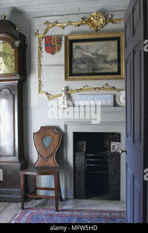 Ein Detail einer traditionellen Wohnzimmer mit einem hölzernen Stuhl in zwischen eine große Standuhr und einem Kamin. Stockfoto