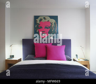 Modernes Schlafzimmer mit bunten Kissen und einem großen Pop art Gemälde über dem Bett. Stockfoto