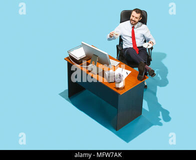 Aufnahme von oben auf eine stilvolle Geschäftsmanns, der auf dem Laptop. Junge glücklicher Mann am Tisch sitzen. Business und Workplace Konzept. Menschliche Gefühle eine Stockfoto