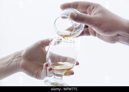 Männliche Hand gießen Alkohol in ein Glas für Frauen Stockfoto