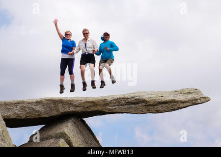 Drei glückliche Wanderer, die vor dem Berg Glyder Fach im Snowdonia National Park vor dem Sprung aus Freude auf der Felsplatte der Auslegerschnepfe stehen. Wales UK Stockfoto