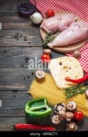 Pasta Zutaten. Cherry-Tomaten, Spaghetti Pasta, Hähnchenfilet und Pilze auf dem Holztisch Stockfoto