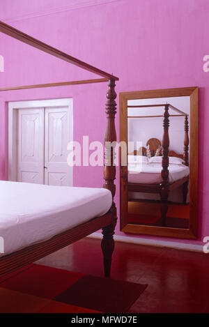Rechteckiger Spiegel an der Wand Himmelbett in rosa Schlafzimmer widerspiegelt Stockfoto