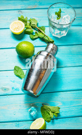 Mojito Cocktail. Minze, Kalk, Glas, Eis, Zutaten und Shaker auf Blau Holz Hintergrund Stockfoto