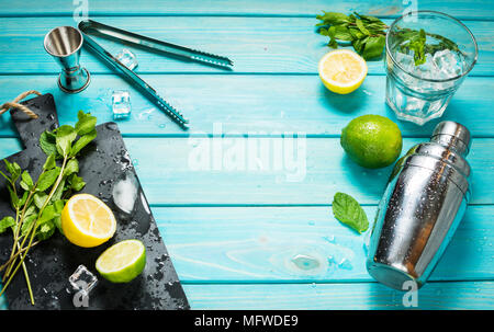 Mojito Cocktail. Minze, Kalk, Glas, Eis, Zutaten und Shaker auf Blau Holz Hintergrund. Platz kopieren Stockfoto