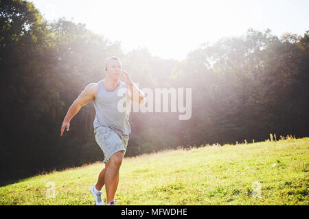 Fitness Mensch Sportler Joggen in der Natur während des Sonnenuntergangs. Person, die einen aktiven Lebensstil Training cardio im Sommer in Sportswear und Schuhe. Stockfoto