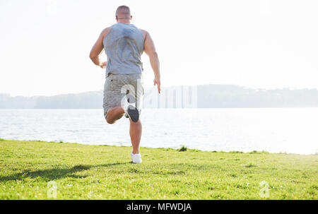 Fitness Mensch Sportler Joggen in der Natur während des Sonnenuntergangs. Person, die einen aktiven Lebensstil Training cardio im Sommer in Sportswear und Schuhe. Stockfoto