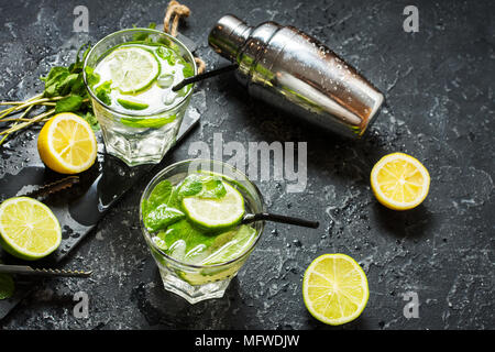 Mojito Cocktail mit Limetten und Minze in highball Glas auf einem Tisch aus Stein. Trinken Sie Werkzeuge und Zutaten für einen Cocktail. Stockfoto