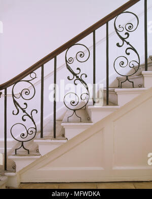 Ein Detail einer traditionellen Flur mit einer Treppe mit dekorativen gescrollt Schmiedeeisen Spindeln, Holz Geländer Stockfoto